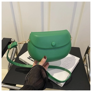 Detail view of emerald green saddle bag featuring matte flap and gold metal hardware hooks