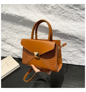 Détail d'un sac à main en cuir marron avec fermoir doré et doubles poignées chic