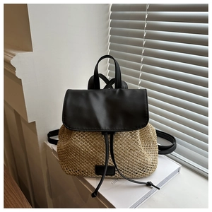 Detail of the woven straw texture and black leather flap on the casual mini backpack