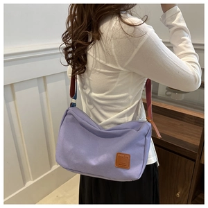 Detail view of large lavender canvas tote bag with colorful strap worn by model