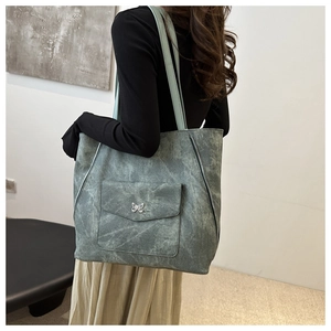 Détails du sac cabas à texture marbrée avec papillon en métal et zips latéraux