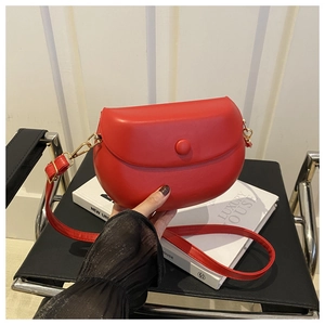 Detail of red faux leather saddle bag featuring a gold buckle and adjustable strap