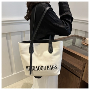 Canvas tote bag with black handles and Mimoaoou lettering shown on a female shoulder