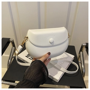Detail of white saddle bag with matte finish and elegant gold hardware on white books