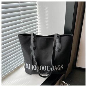 Detail view of a black canvas tote bag with white lettering on a window sill with soft shadows