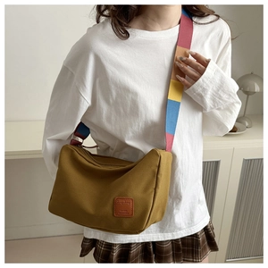 Detail of ginger canvas messenger bag featuring a vibrant multi-color rainbow wide strap