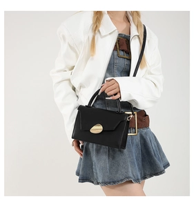 Close-up of stylish contrast crossbody bag with gold metal buckle on model