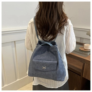 Détail du sac à dos bleu denim avec logo papillon argenté et texture mate chic