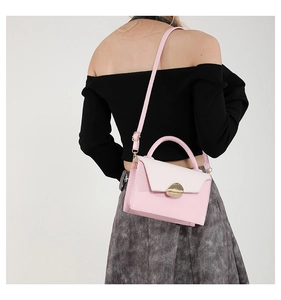 Detail of pink and cream crossbody bag with gold buckle on a model in casual outfit