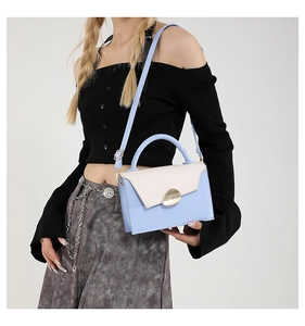 Detail of blue and white contrast handbag with elegant gold metal twist lock closure