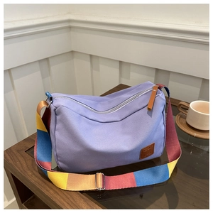 Detail of lavender canvas tote with colorful woven strap and brown leather logo patch