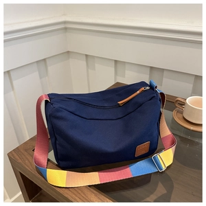 Detail of navy canvas tote with colorful woven strap and brown leather logo patch