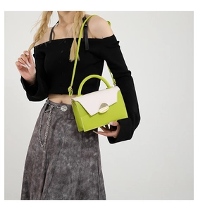 Close-up of contrast color crossbody bag with green body and golden metallic buckle