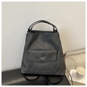 Détail du sac à dos en faux daim gris foncé avec boucle papillon argentée sur cuir