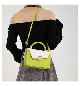 Side view of trendy green and cream crossbody bag with gold lock worn by a model