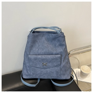 Détail du sac bleu en daim synthétique avec boucle décorative papillon en métal