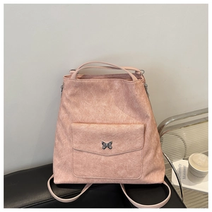 Détail du sac fourre-tout rose mat avec papillon décoratif en métal sur la poche extérieure