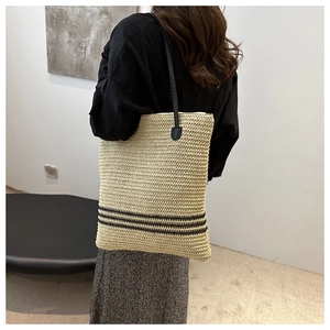 Détail du sac cabas en paille tressée avec rayures noires et fines bandoulières