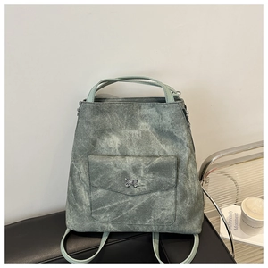 Détail d'un sac à dos vert clair à texture délavée avec ornement papillon argenté