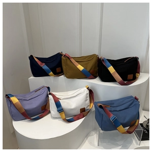 Detailed view of canvas pillow bags in six colors with multi-colored wide straps