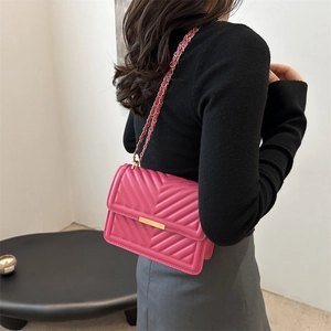 Fuchsia V-quilted crossbody bag with gold chain strap shown on model's shoulder