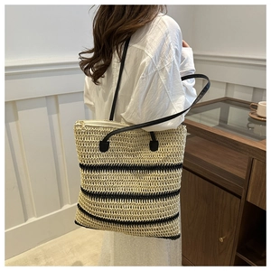 Macro detail of large woven straw tote bag with black stripes and secure zipper closure