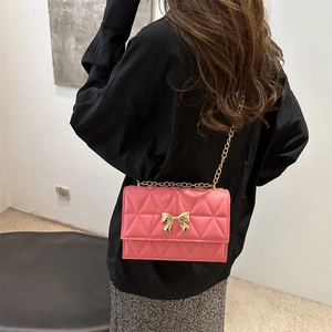 Pink quilted bow crossbody bag with gold chain strap shown from a back-wearing perspective