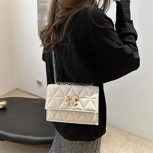Cream crossbody bag with geometric quilting and a golden bow accent for women