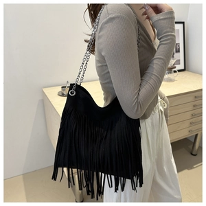 Fashionable black fringe tote bag with metal chain strap in bohemian street style