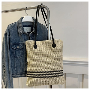 Détail d'un sac cabas tissé avec fond à rayures noires et longues bandoulières noires