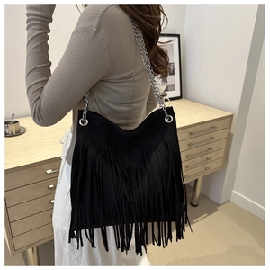 Détail d'un sac hobo en daim noir avec de longues franges et des bandoulières en chaîne