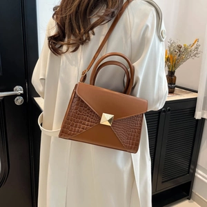 Brown leather crossbody handbag with crocodile pattern panels and gold pyramid clasp