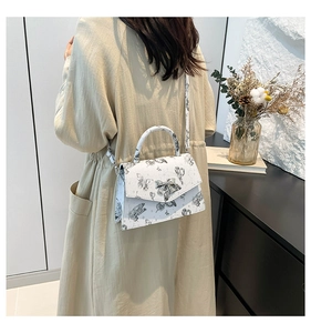 Detailed back view of a white crossbody bag with butterfly prints worn on a beige coat