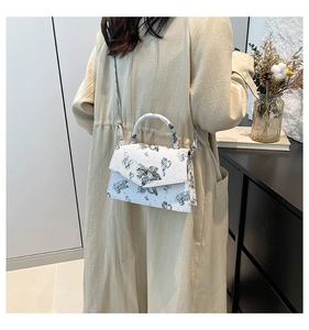 Detail of butterfly print crossbody bag featuring silver bow clasp and slim shoulder strap