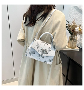 Side view of white butterfly print crossbody bag worn by model in a modern home setting