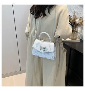 Detail of white PU tote bag with green butterfly prints and silver bow metal clasp