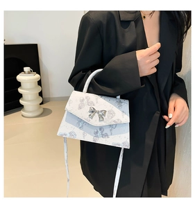 Detail of white tote bag with blue butterfly patterns and metal bow buckle decoration