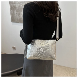 Silver crocodile textured crossbody bag with fringe tassel shown on a shoulder