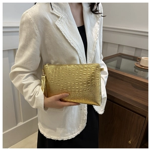 Detail of gold clutch bag with embossed crocodile texture and matching wrist strap