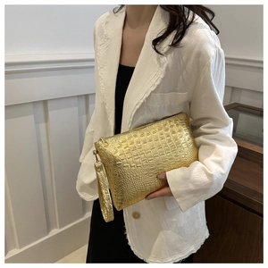 Detail of metallic gold crocodile pattern handbag showing rich texture and top wrist strap