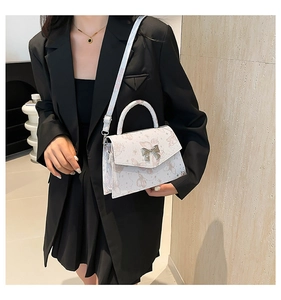 Close-up of white tote bag with butterfly prints and silver bow metal buckle detail