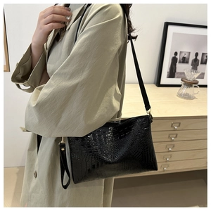 Detail of a black crocodile pattern crossbody bag on a khaki trench coat model