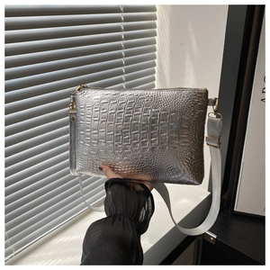 Detail of silver crocodile embossed crossbody bag with wide grey shoulder strap