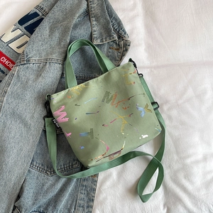 Detail of light green crossbody bag with colorful graffiti print and adjustable strap