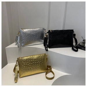 Three crocodile embossed clutches in gold, silver, and black on minimalist steps