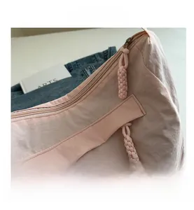 Detail of light pink nylon shoulder bag showing woven zipper pull and fashion label