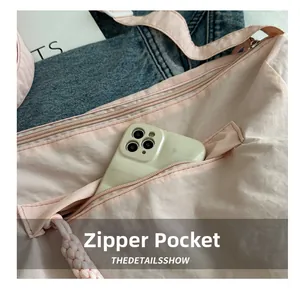 Detailed close-up of a pink nylon crossbody bag showing the functional front zipper pocket