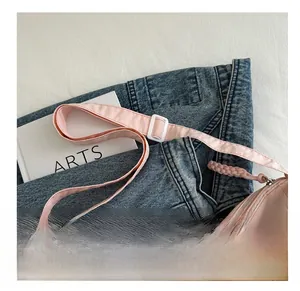 Detail of pink crossbody bag showing adjustable strap with white buckle and zipper