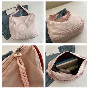 Detail view of pink nylon crossbody bag with woven zipper pull and spacious interior