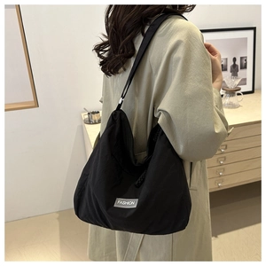 Close-up of black nylon tote bag featuring a white Fashion woven label on the bottom